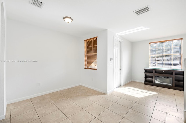 empty room with light tile patterned flooring, baseboards, and visible vents