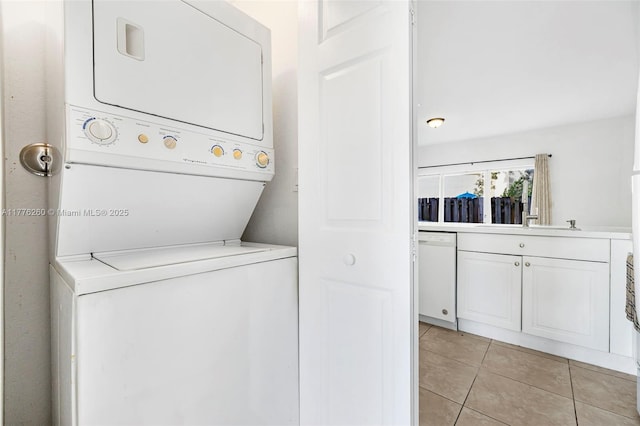laundry room featuring stacked washer / dryer, laundry area, and light tile patterned floors