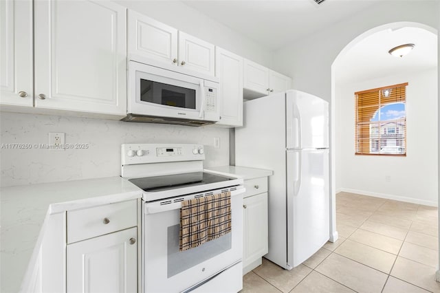 kitchen with white cabinetry, light countertops, arched walkways, and white appliances