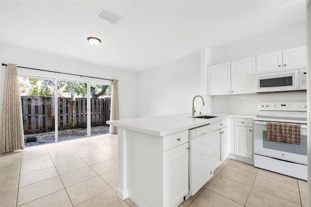 kitchen featuring a sink, a peninsula, light tile patterned floors, white appliances, and visible vents