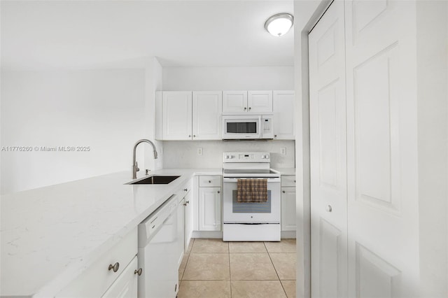 kitchen featuring light tile patterned flooring, light countertops, white appliances, white cabinetry, and a sink