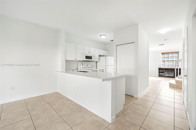 kitchen with a peninsula, light countertops, light tile patterned floors, and white appliances