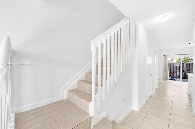 stairs with baseboards and tile patterned flooring