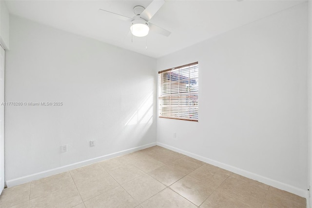 empty room with baseboards, ceiling fan, and light tile patterned floors