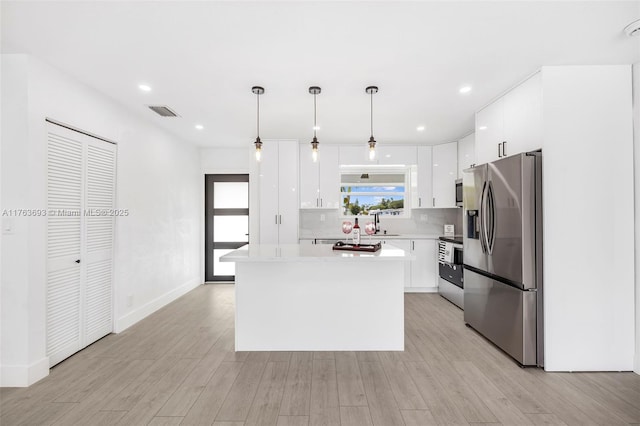 6335 Southgate Blvd, Margate, FL 33068 - kitchen with stainless steel appliances, white cabinetry, light countertops, a kitchen island, and light wood finished floors