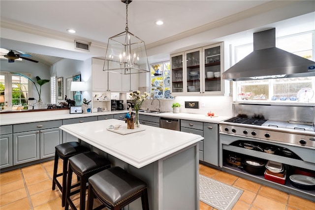 kitchen with gray cabinetry, ventilation hood, a sink, and stainless steel dishwasher