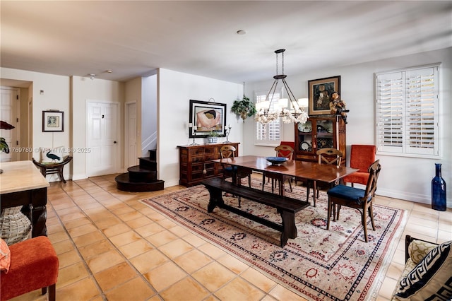 dining room with light tile patterned floors, a notable chandelier, baseboards, and stairway