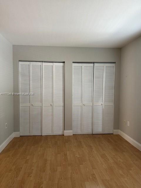2607 NW 33rd St Unit 2111, Oakland Park, FL 33309 - unfurnished bedroom featuring baseboards, multiple closets, and light wood-style floors