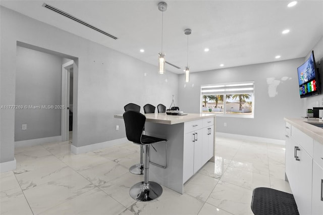 9025 SW 56th St, Miami, FL 33165 - kitchen with recessed lighting, baseboards, white cabinetry, light marble finish flooring, and light countertops