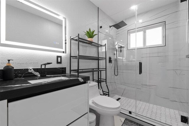 9025 SW 56th St, Miami, FL 33165 - bathroom with toilet, vanity, a marble finish shower, a textured wall, and marble finish flooring