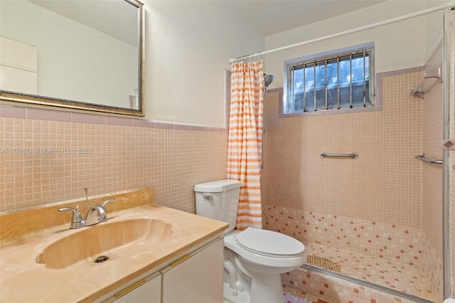 bathroom featuring tile walls, toilet, vanity, tiled shower, and wainscoting