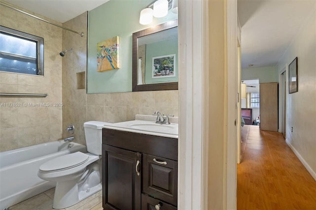 bathroom with plenty of natural light, tub / shower combination, vanity, and tile walls