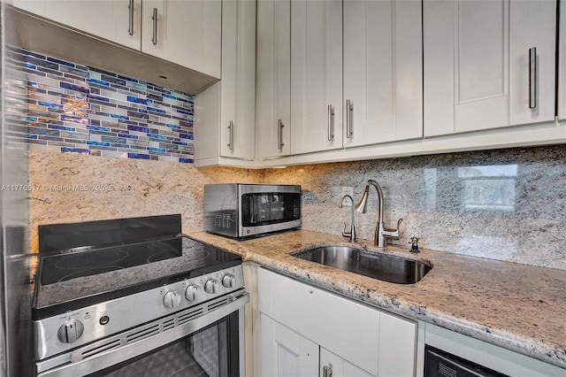 kitchen with white cabinets, decorative backsplash, stainless steel appliances, and a sink