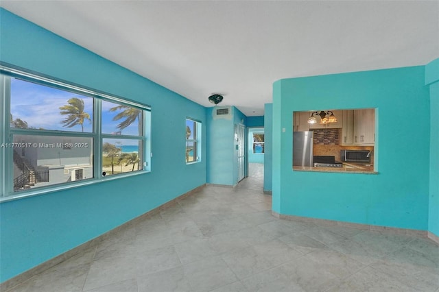 tiled empty room with baseboards, visible vents, and an inviting chandelier