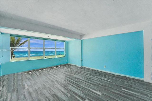 spare room featuring baseboards, wood finished floors, and a water view
