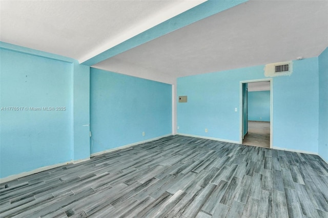 unfurnished room featuring baseboards, wood finished floors, and visible vents