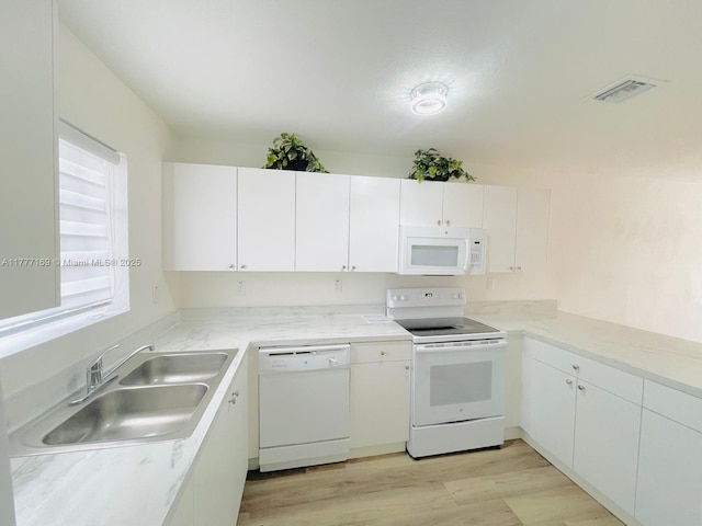 kitchen with white cabinetry, white appliances, a sink, visible vents, and light wood-style flooring