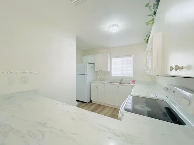 kitchen featuring light wood finished floors, white appliances, white cabinetry, a sink, and light stone counters