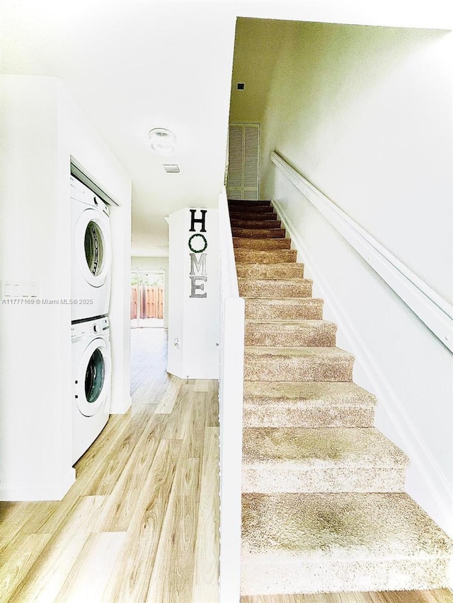 stairway featuring stacked washer and clothes dryer and wood finished floors