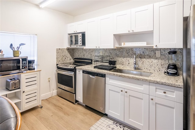 kitchen with open shelves, white cabinets, appliances with stainless steel finishes, a sink, and decorative backsplash