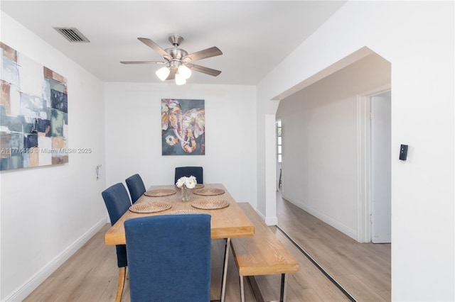 dining area featuring light wood finished floors, baseboards, a ceiling fan, and visible vents