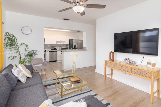 living area featuring visible vents, ceiling fan, light wood finished floors, and baseboards