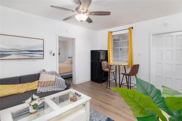 living area featuring light wood finished floors and ceiling fan