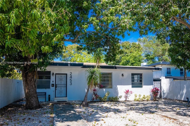 ranch-style house with stucco siding and fence