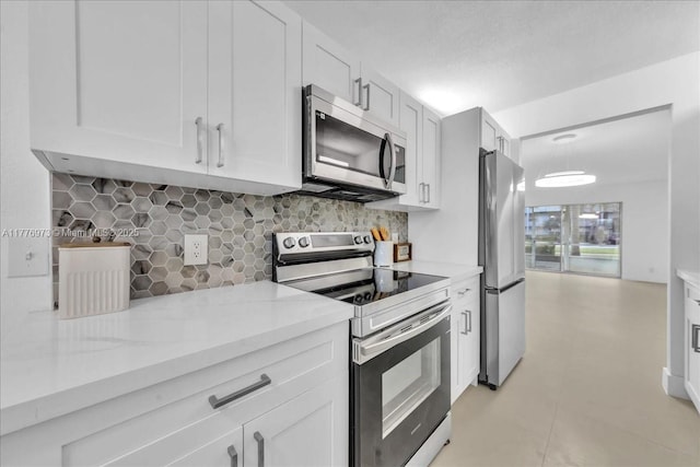 650 SW 124th Ter Unit 105P, Pembroke Pines, FL 33027 - kitchen featuring appliances with stainless steel finishes, decorative backsplash, light stone countertops, and white cabinets
