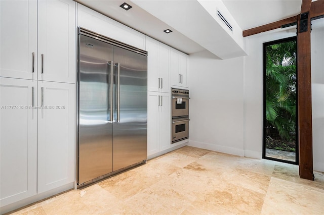 kitchen featuring baseboards, white cabinetry, visible vents, and stainless steel appliances