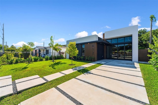 contemporary home featuring a front yard, fence, and stucco siding