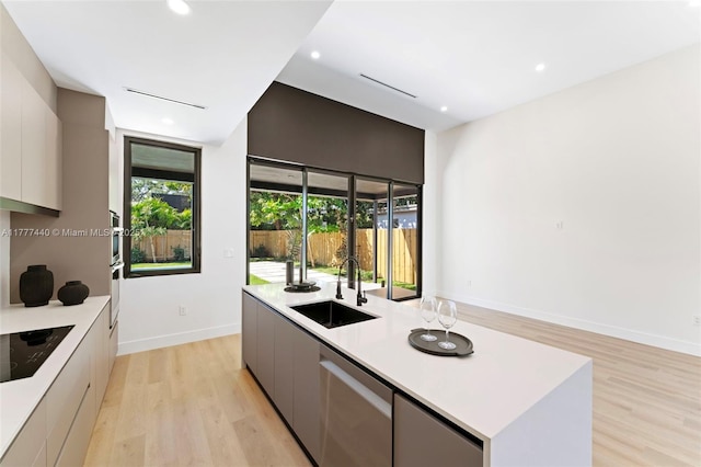 kitchen featuring light countertops, a sink, appliances with stainless steel finishes, modern cabinets, and light wood-type flooring