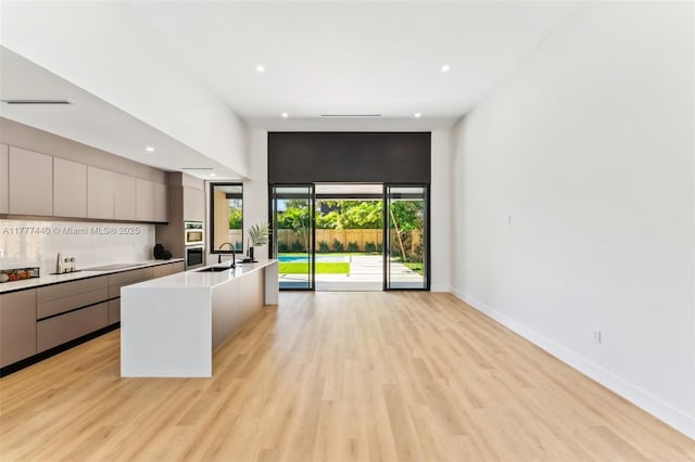 kitchen featuring open floor plan, gray cabinets, modern cabinets, and light wood-style floors