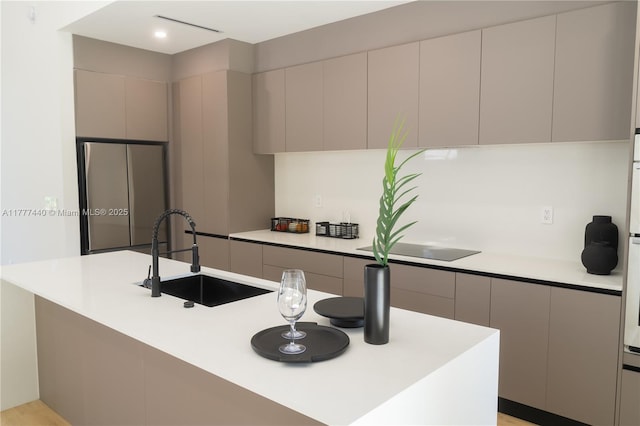 kitchen with modern cabinets, black electric cooktop, a sink, and light countertops