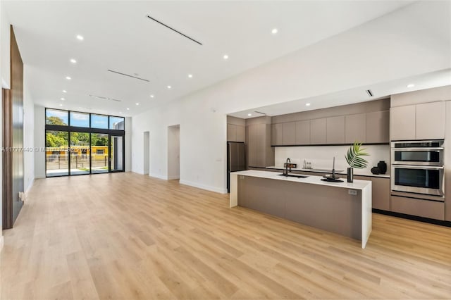 kitchen featuring expansive windows, a sink, appliances with stainless steel finishes, modern cabinets, and open floor plan