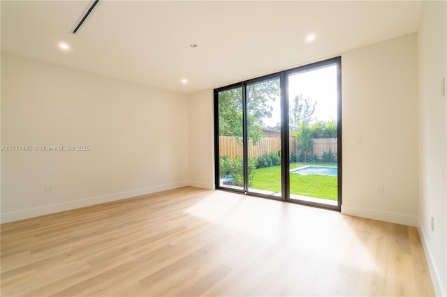 spare room featuring light wood-style flooring, baseboards, expansive windows, and visible vents