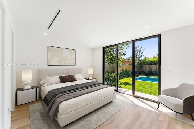 bedroom with light wood finished floors, access to outside, expansive windows, and visible vents