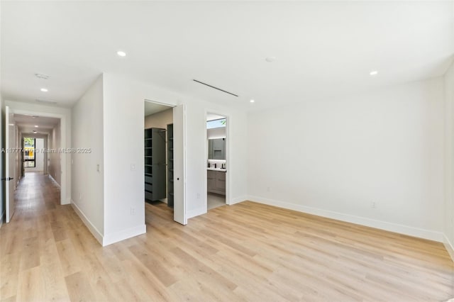 spare room with baseboards, light wood finished floors, and recessed lighting