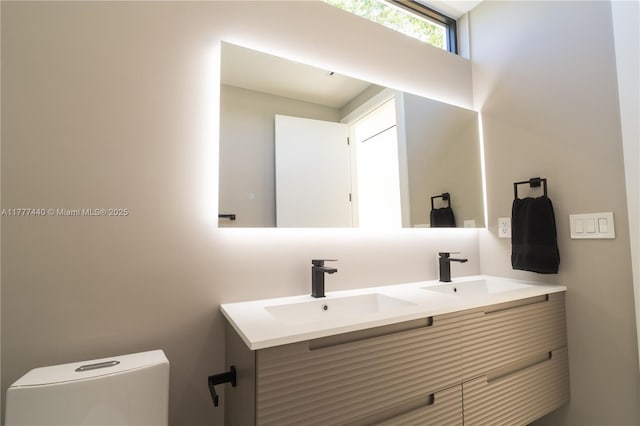 bathroom with double vanity, toilet, and a sink