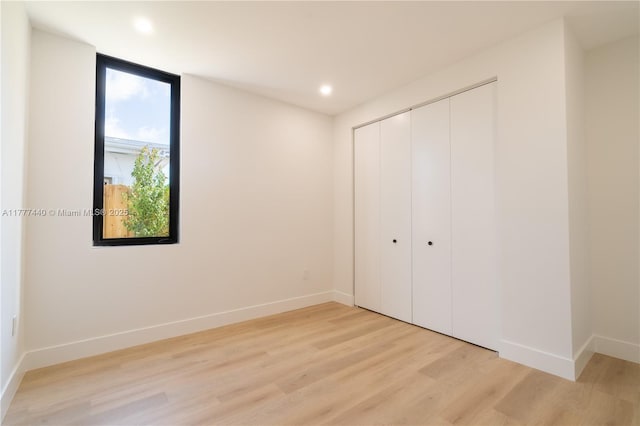unfurnished bedroom with light wood-style flooring, a closet, baseboards, and recessed lighting