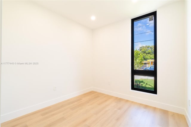 empty room featuring baseboards, expansive windows, light wood-style floors, and recessed lighting