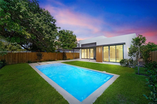 view of swimming pool featuring a lawn, a fenced in pool, a fenced backyard, and a patio