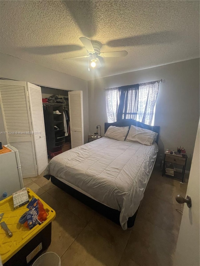 tiled bedroom with a closet, a textured ceiling, and ceiling fan