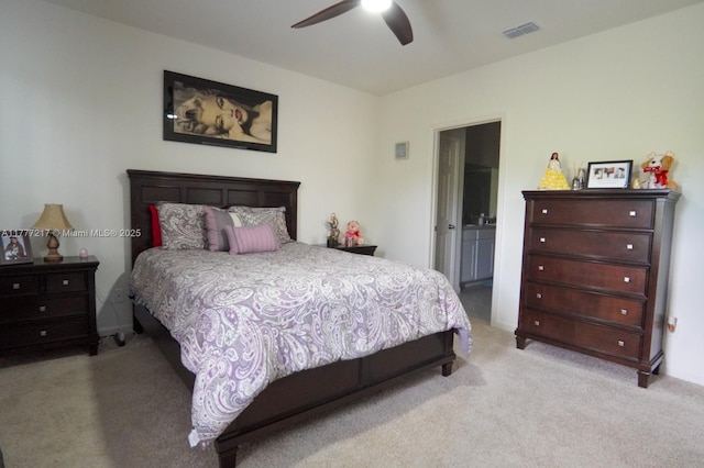 carpeted bedroom featuring ensuite bathroom, visible vents, and a ceiling fan