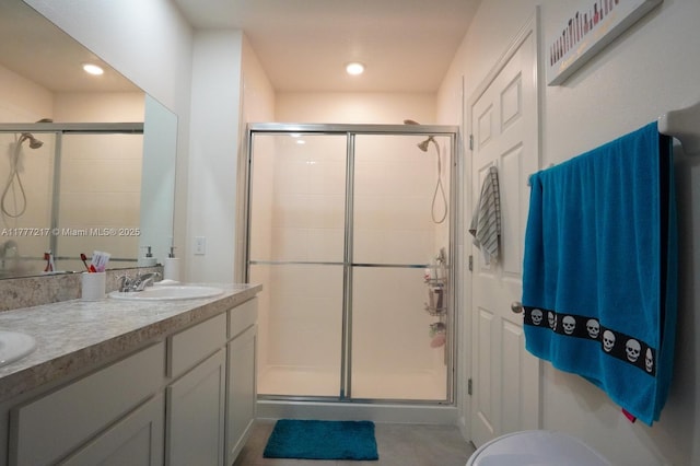 full bath featuring double vanity, a sink, and a stall shower