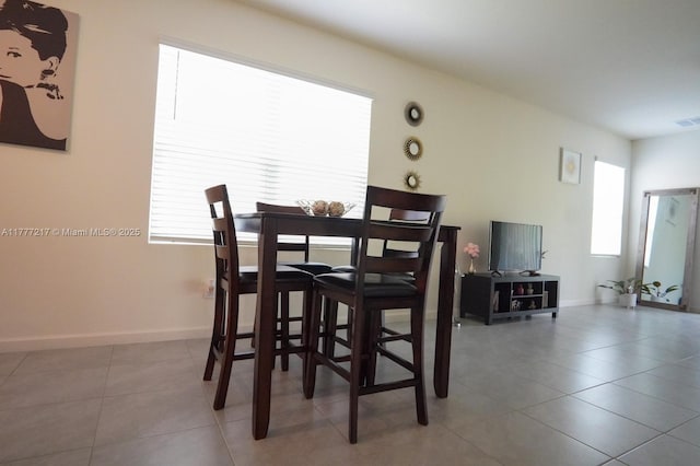 tiled dining space with baseboards and visible vents