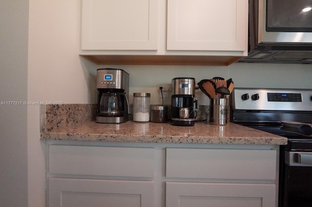 kitchen featuring white cabinetry, light stone countertops, and appliances with stainless steel finishes