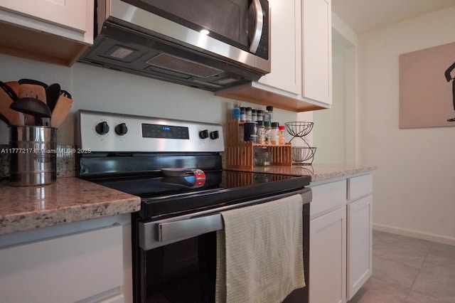 kitchen with white cabinetry, light tile patterned floors, baseboards, light stone countertops, and appliances with stainless steel finishes