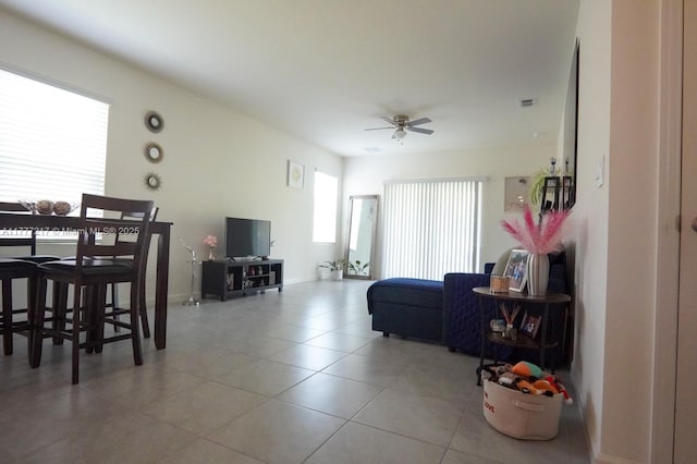 living area with baseboards, visible vents, tile patterned flooring, and a ceiling fan