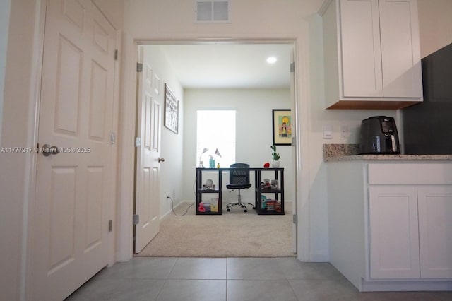 hallway with light tile patterned flooring, light colored carpet, and visible vents